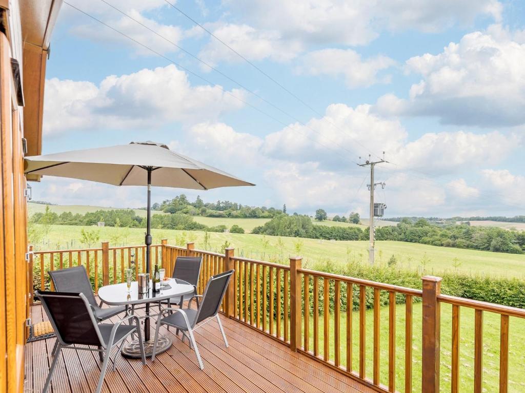 a wooden deck with a table and chairs and an umbrella at 2 Bed in Kinlet 92657 in Kinlet
