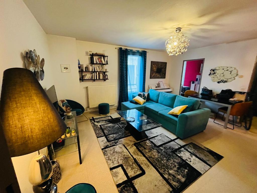 - un salon avec un canapé bleu et une table dans l'établissement Cosy appartement Rives du lez, à Montpellier