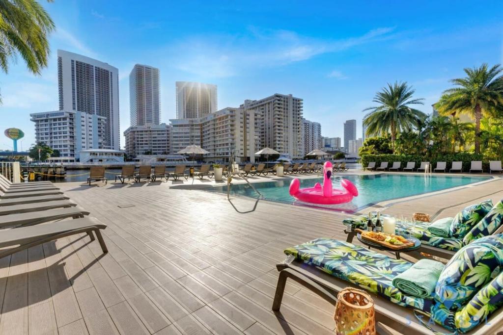 a large swimming pool with a city skyline in the background at Condo Retreat with Stunning Views and Amazing Pools in Hallandale Beach