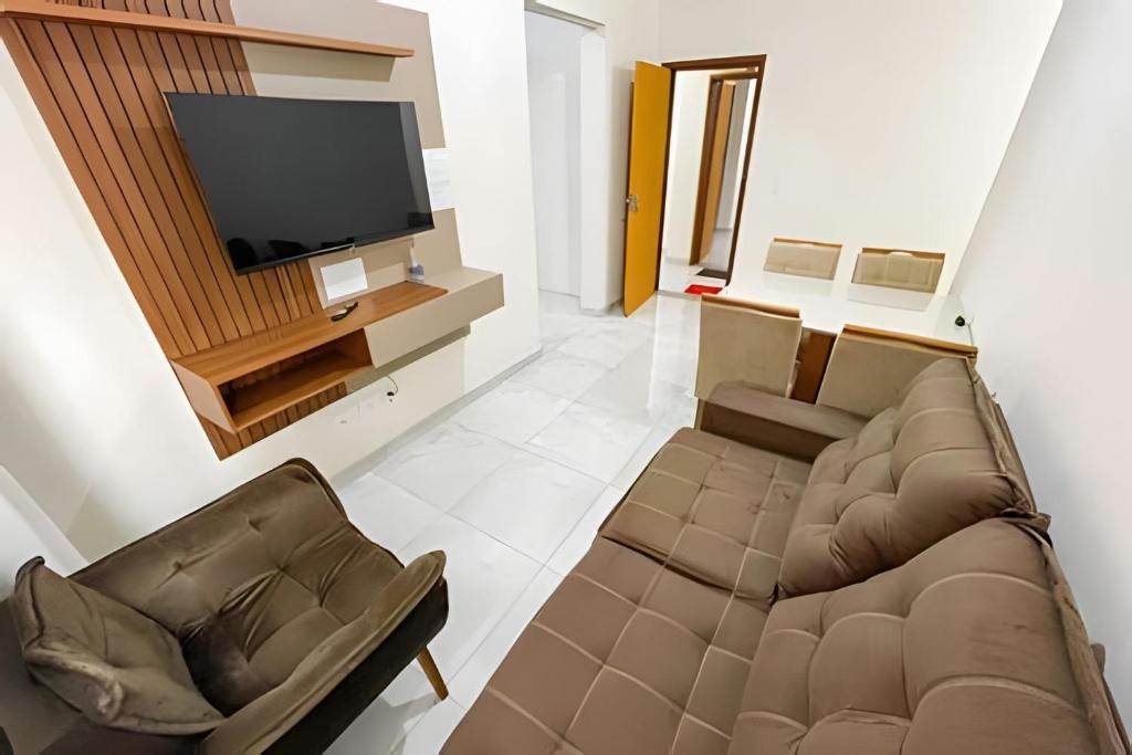 uma sala de estar com um sofá e uma televisão de ecrã plano em 104 - Apartamento Completo para até 7 Hóspedes em Patos de Minas