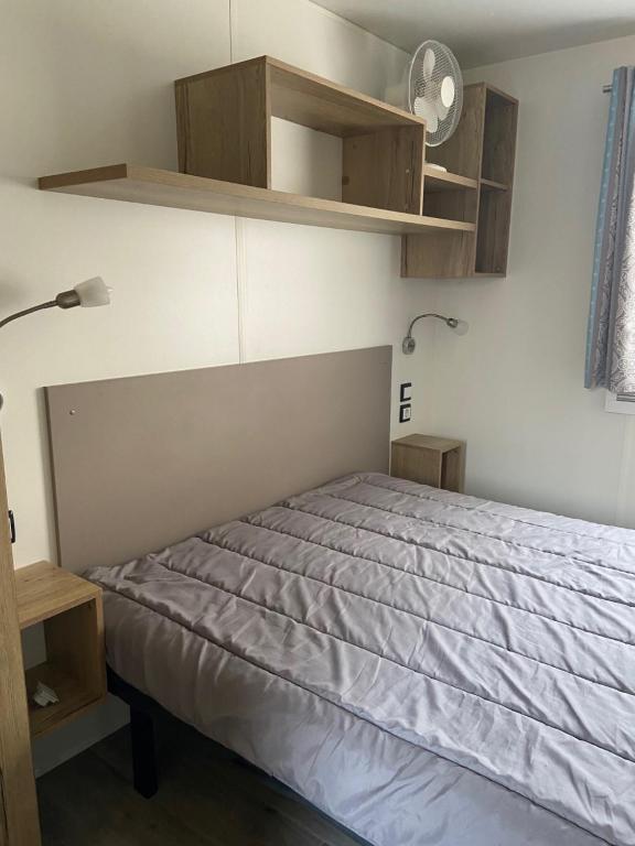 - une chambre avec un lit, des étagères et une lampe dans l'établissement MOBIL HOME 2 CHAMBRES CLIMATISE, à Gastes