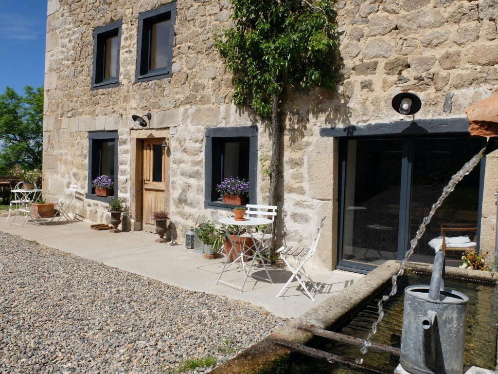 een stenen huis met een tafel en stoelen buiten bij la source d'en haut in Valcivières