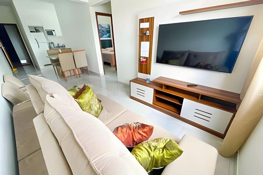 uma sala de estar com um sofá branco e uma televisão em 202- APARTAMENTO de 2 QUARTOS para até 5 HÓSPEDES em Patos de Minas