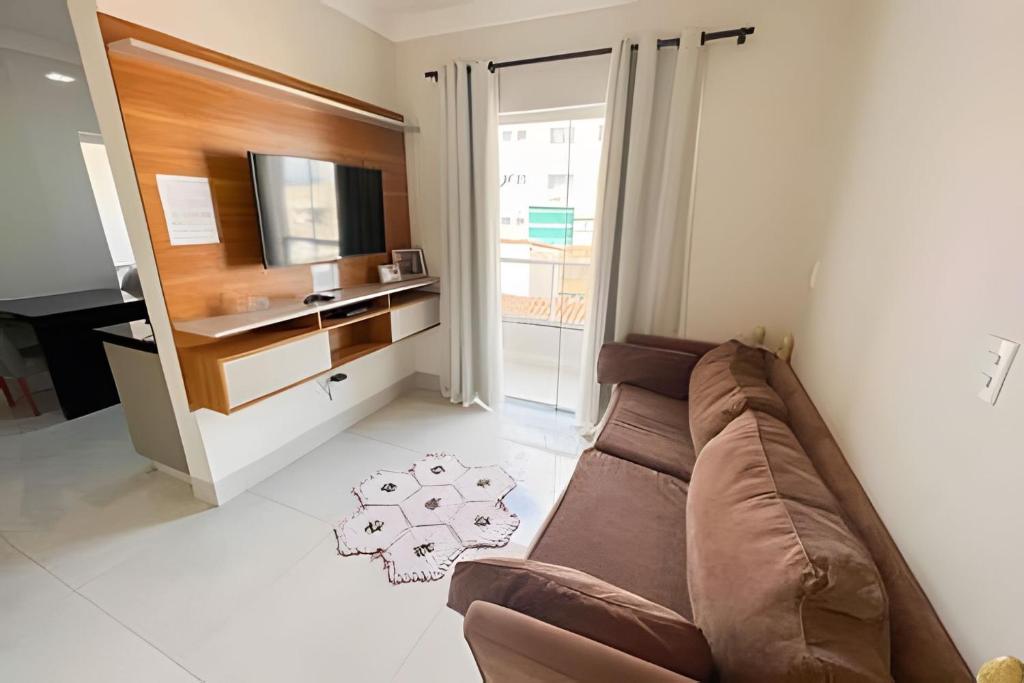uma sala de estar com um sofá castanho e uma televisão em M203- Apartamento c/ Suíte Completo Patos de Minas em Patos de Minas