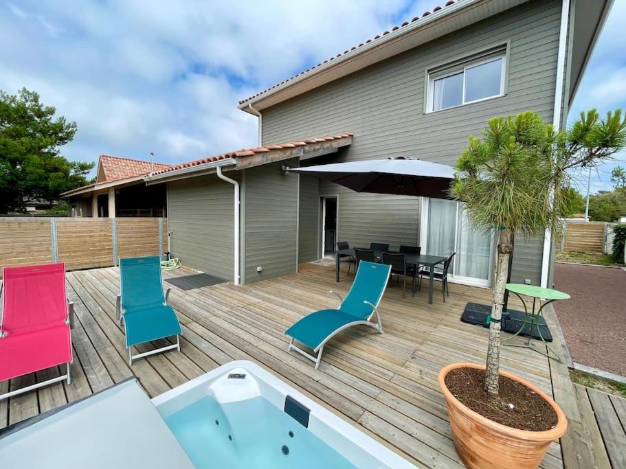 a deck with chairs and a table and a tree at Welcoming new architects house with jacuzzi in Hourtin