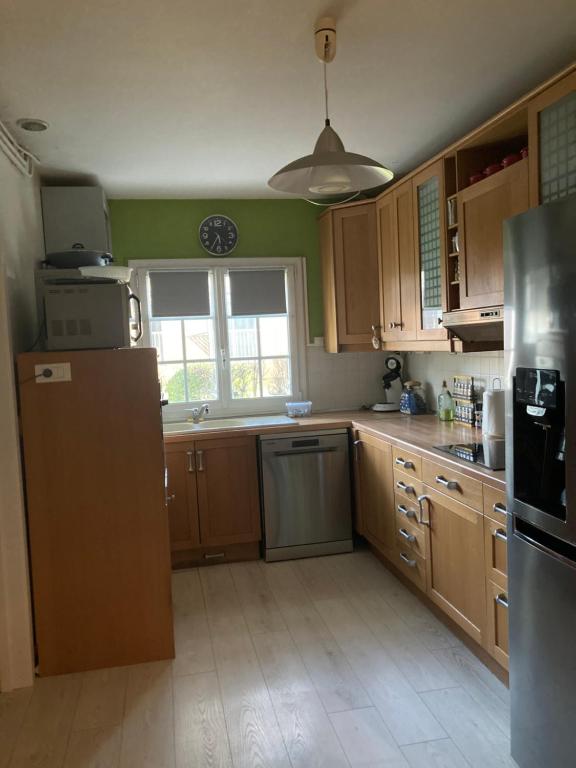 a kitchen with wooden cabinets and a refrigerator and a window at Jolie petite maison avec jardin ! in La Queue-en-Brie