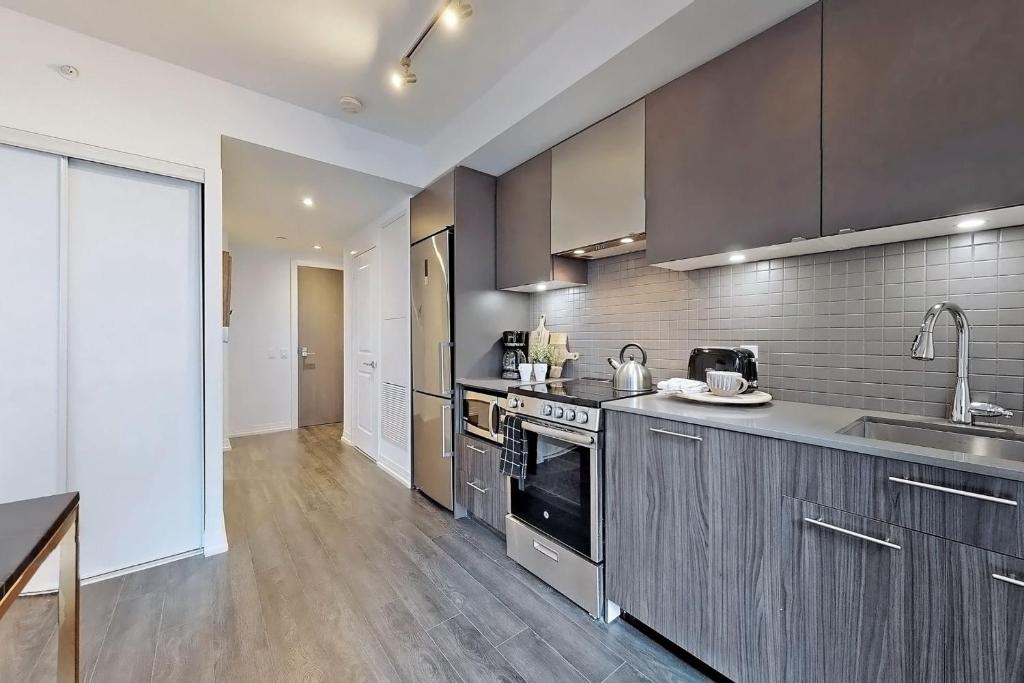a large kitchen with stainless steel appliances and wooden floors at Cozy Suite in Heart of Downtown Toronto J7 in Toronto