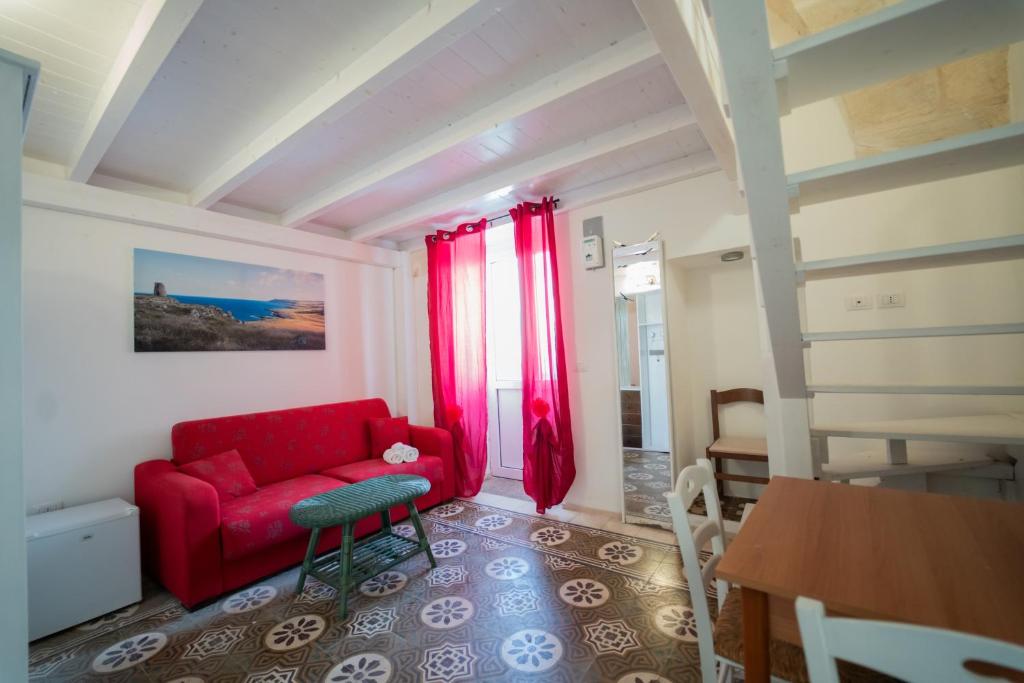 ein Wohnzimmer mit einem roten Sofa und einem Tisch in der Unterkunft AFFITTACAMERE ANEMONE- SCIROCCO1 in Uggiano la Chiesa