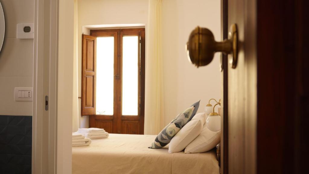 una camera da letto con un letto con lenzuola bianche e una finestra di Santaló B&B a Bitonto