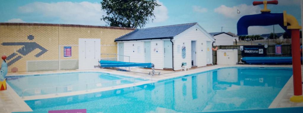 a large swimming pool with a building and a pool slides at Seasalter Cosy Caravan, in Seasalter