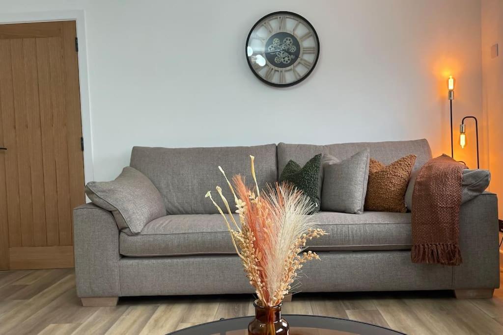a living room with a couch and a clock on the wall at Braeview, Contemporary Luxury NC500 Holiday Home - Sleeps 5 in Wick