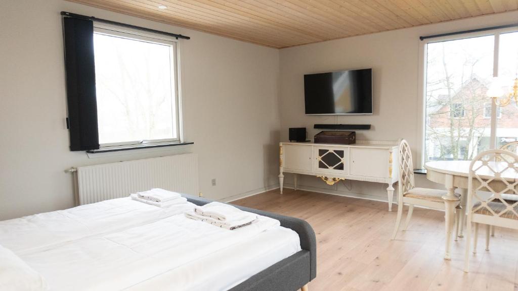 ein Schlafzimmer mit zwei Betten, einem Schreibtisch und einem Fernseher in der Unterkunft Hotel Smedegaarden in Lem
