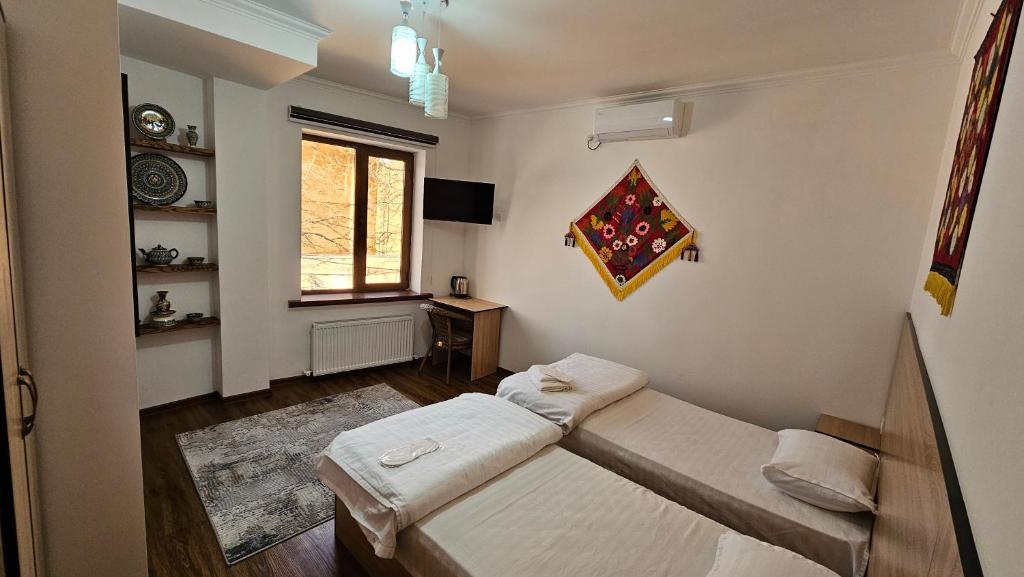 1 dormitorio con 2 camas y ventana en HOTEL MEHRIBON, en Samarkand