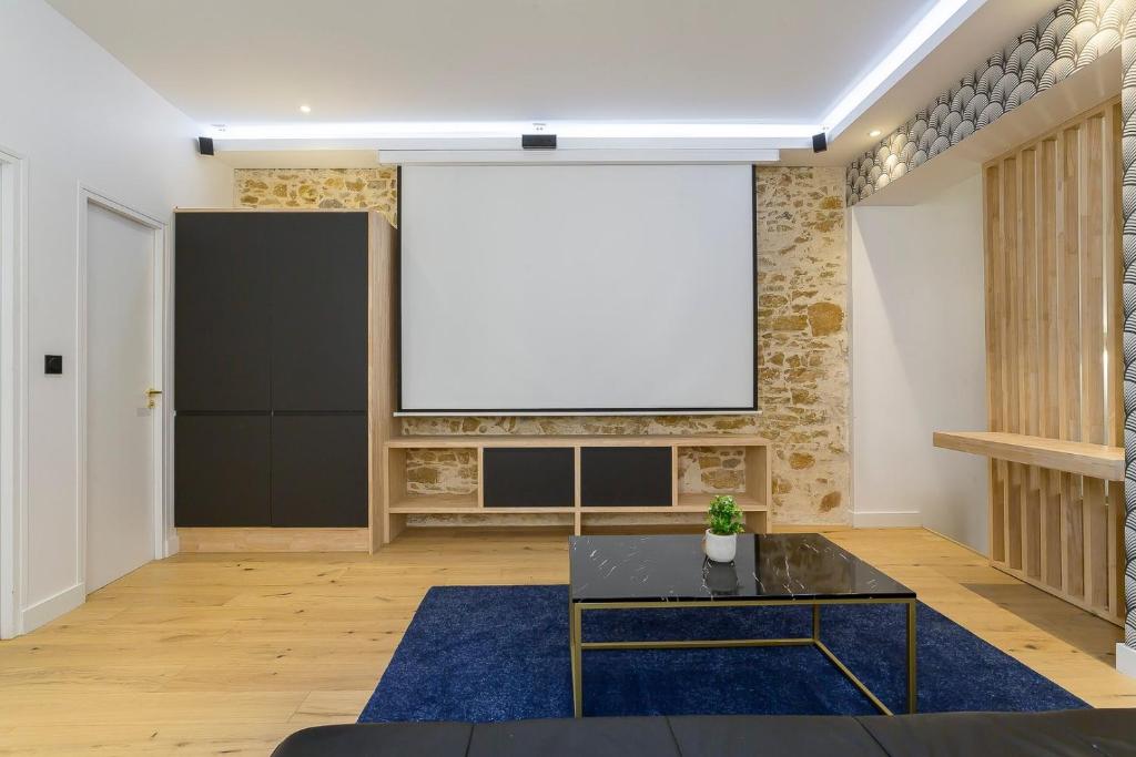 a living room with a large screen on a brick wall at Hamac Suites - Lyon le Bellecour in Lyon