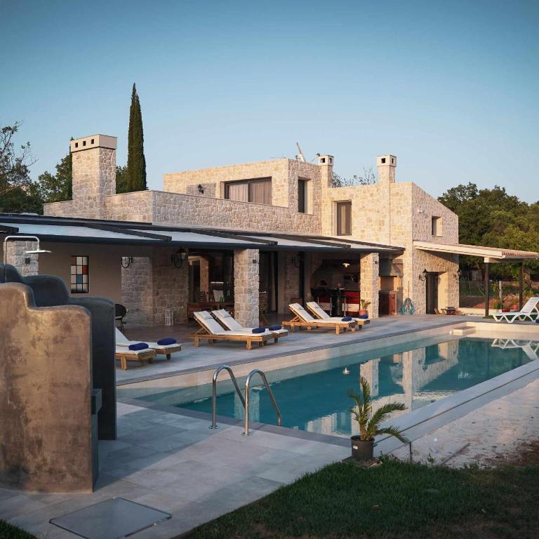 a villa with a swimming pool in front of a house at Villa Stratos Corfu -private pool and hot tub in Corfu