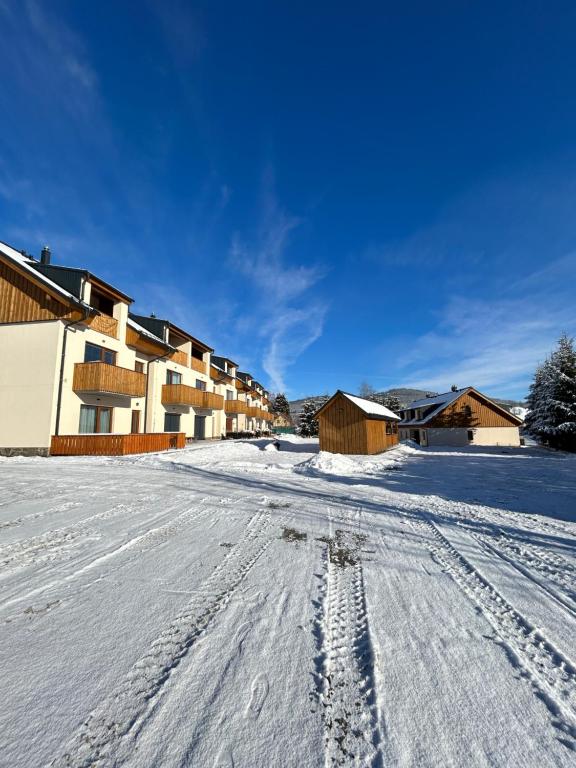 una calle cubierta de nieve con huellas en la nieve en Apartmán A3 Kašperky Slunný moderní apartmán na horách en Kašperské Hory