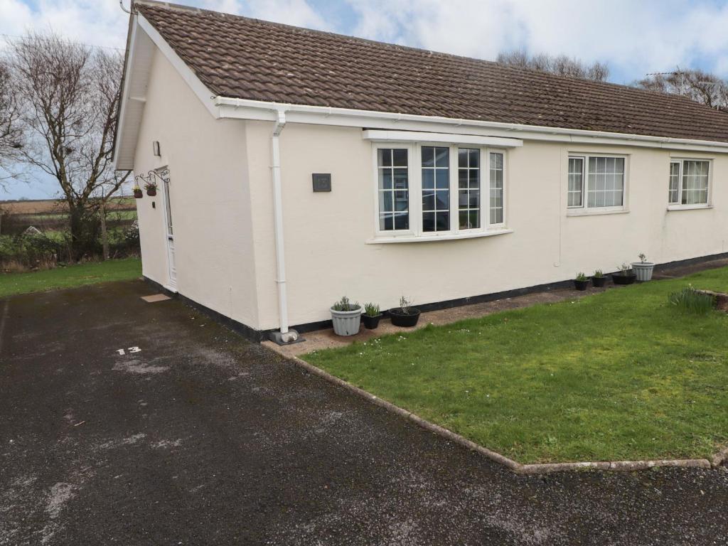 a small white house with a yard at 13 Gower Holiday Village in Swansea