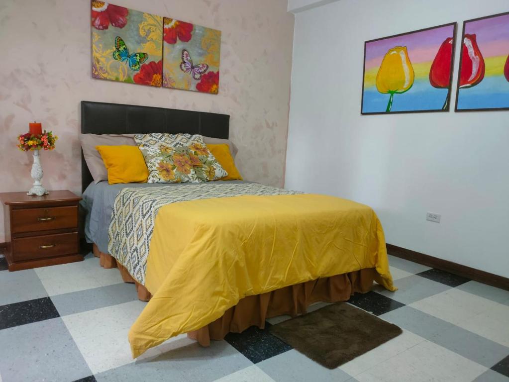 a bedroom with a bed with a yellow comforter at Bryslaungeguayaquil in Guayaquil