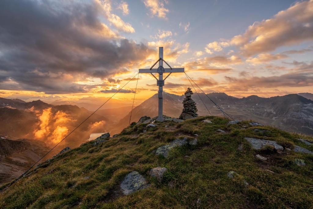 a cross on top of a mountain with the sunset at Hotel Garni Löwen in Silz