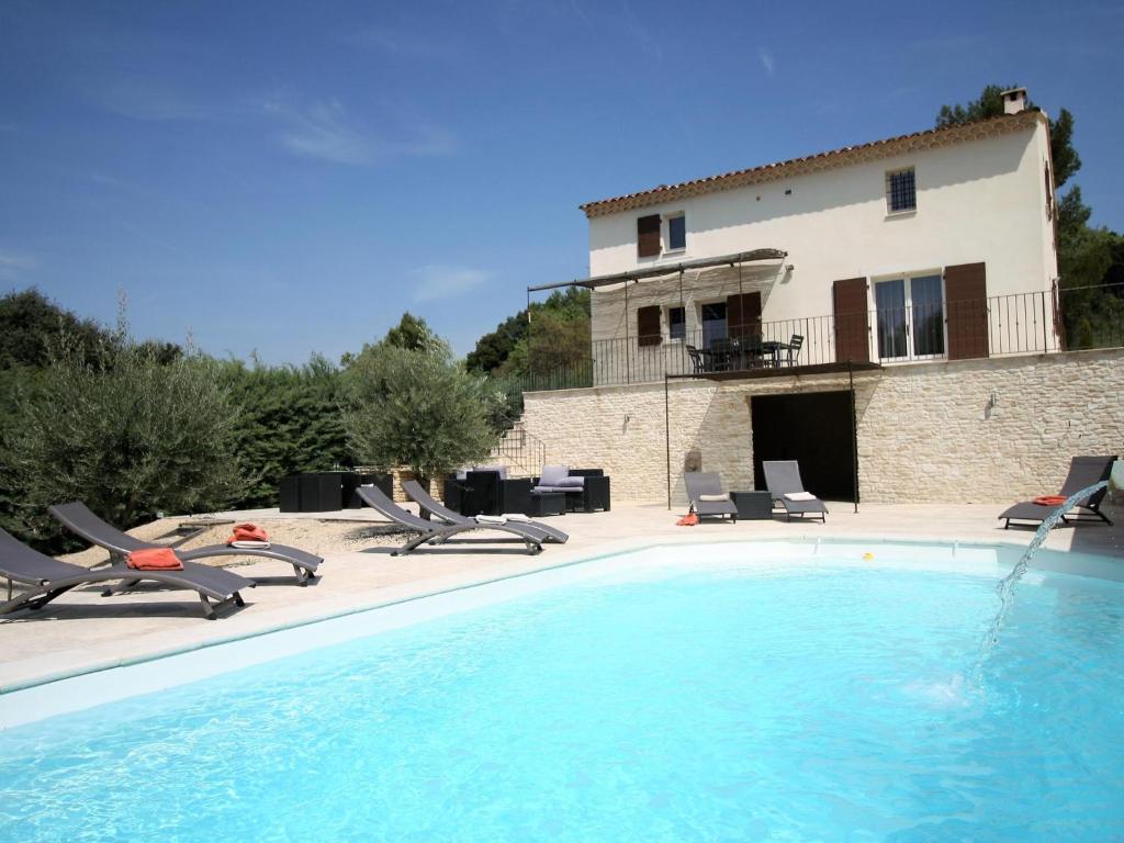 une grande piscine avec des chaises et une maison dans l'établissement Le Mistral, à Apt