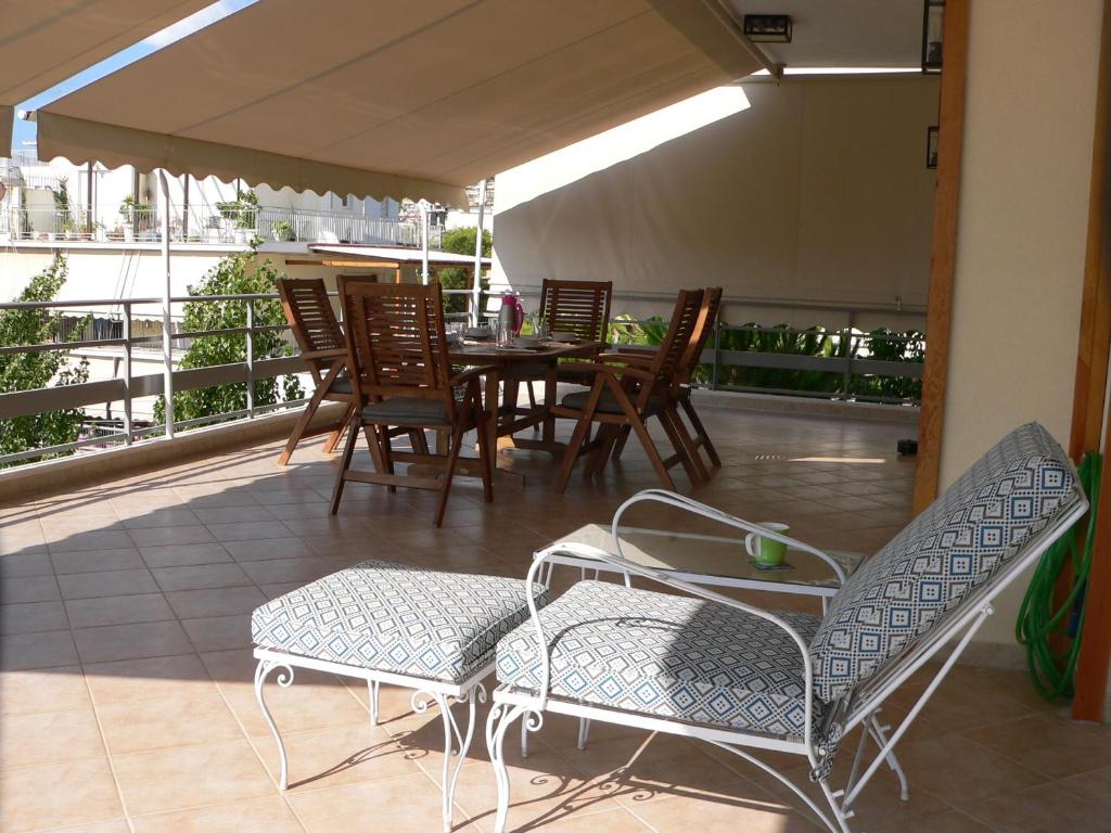 eine Terrasse mit einem Tisch und Stühlen auf dem Balkon in der Unterkunft Breezy Veranda Apartment Varkiza in Vari