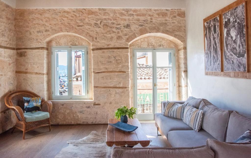 een woonkamer met een bank en 2 ramen bij Wood and Stone Ηouse in Aegina Town