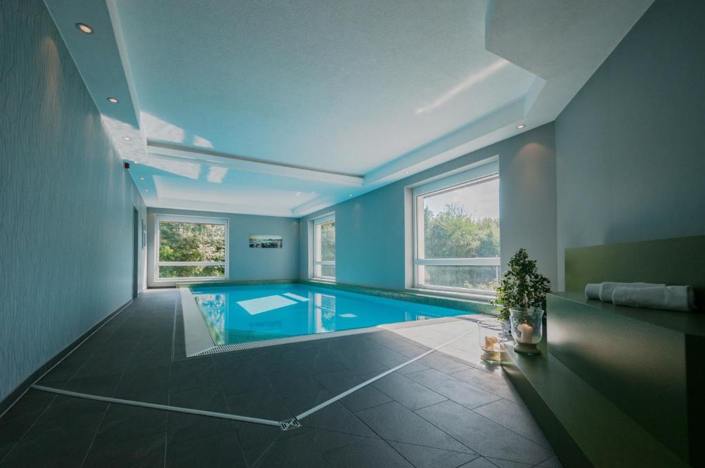 a large room with a swimming pool with blue walls at Hotel Fortuna Reutlingen-Tübingen in Reutlingen