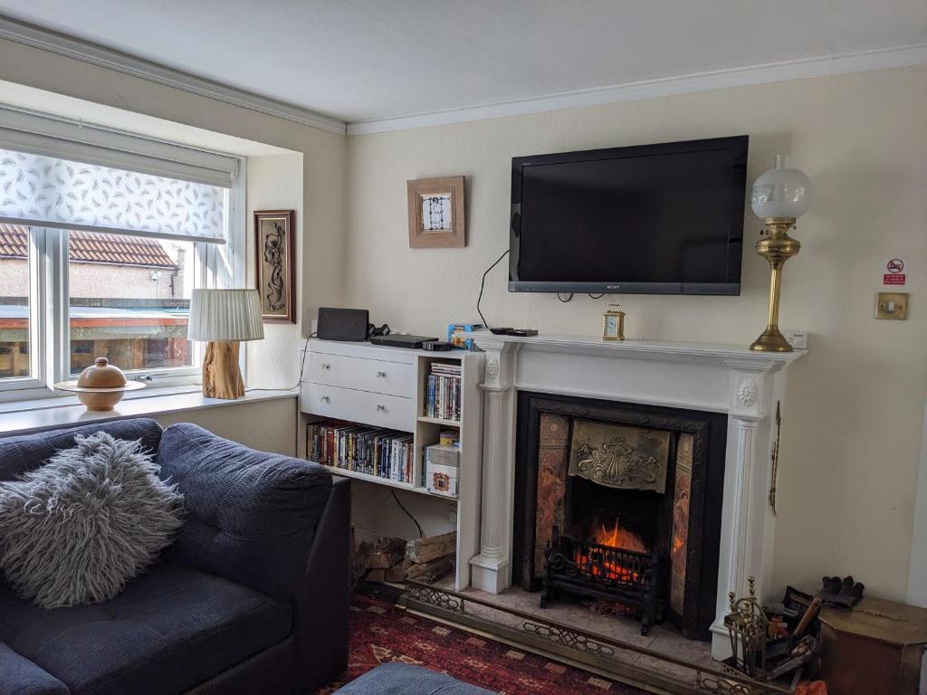 a living room with a fireplace with a tv above it at Craigmile Cottage in Fraserburgh