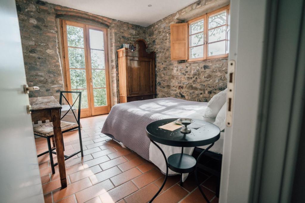 a bedroom with a bed and a table and windows at Agriturismo Le Valli in Casciana Terme
