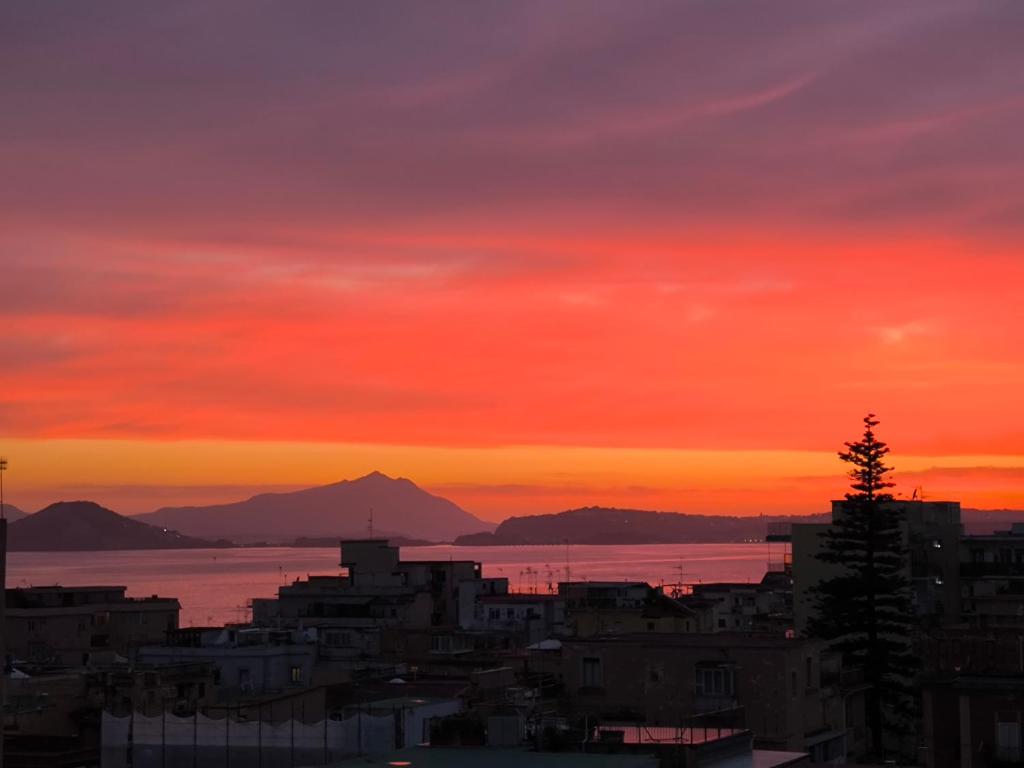 um pôr-do-sol sobre uma cidade com montanhas ao fundo em Seconda Stella a Destra em Nápoles