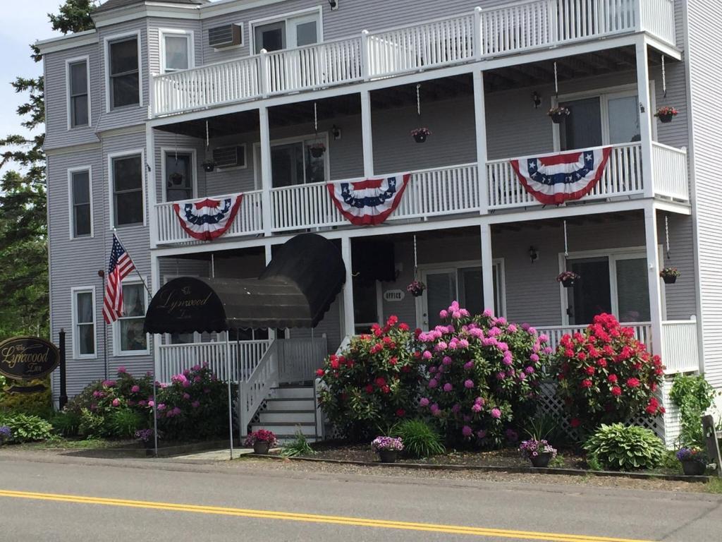 Un edificio con bandiere americane e fiori davanti di Lynwood Inn a York Beach