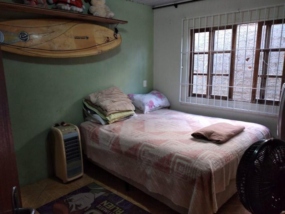 Habitación pequeña con cama y ventana en Casa c/Piscina em Arroio do Rosa en Imbituba
