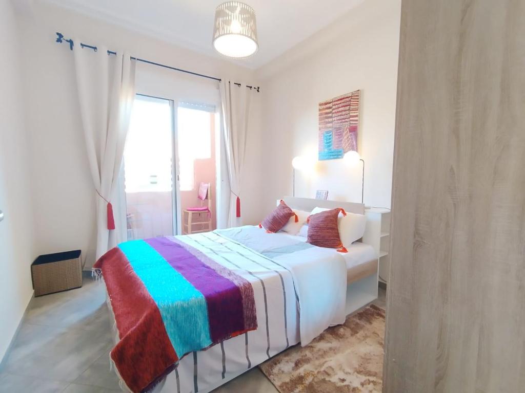 1 dormitorio blanco con 1 cama con una manta colorida en RM 15 by Majestic Properties, en Marrakech