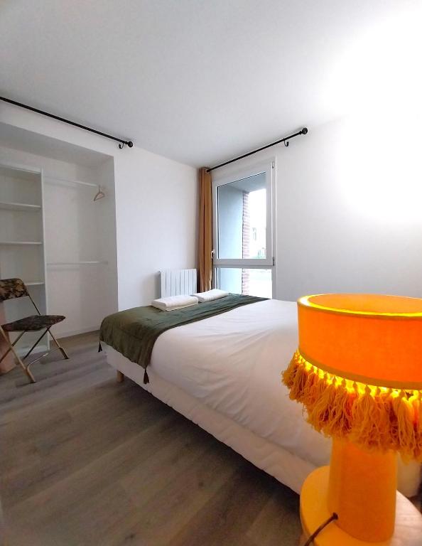 ein Schlafzimmer mit einem großen Bett und einem Fenster in der Unterkunft Gîte-appartement RDC La Ville au Monnier in Pleurtuit