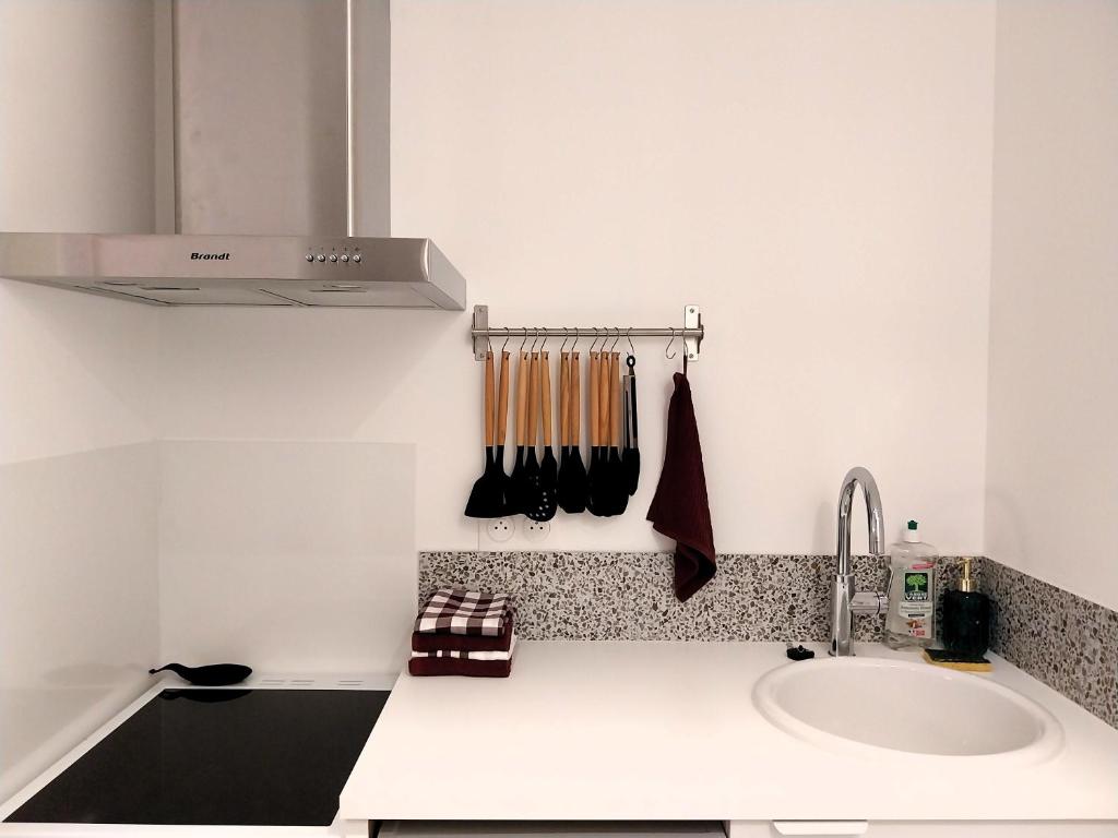 eine weiße Küche mit einem Waschbecken und einer Arbeitsplatte in der Unterkunft Gîte-appartement RDC La Ville au Monnier in Pleurtuit