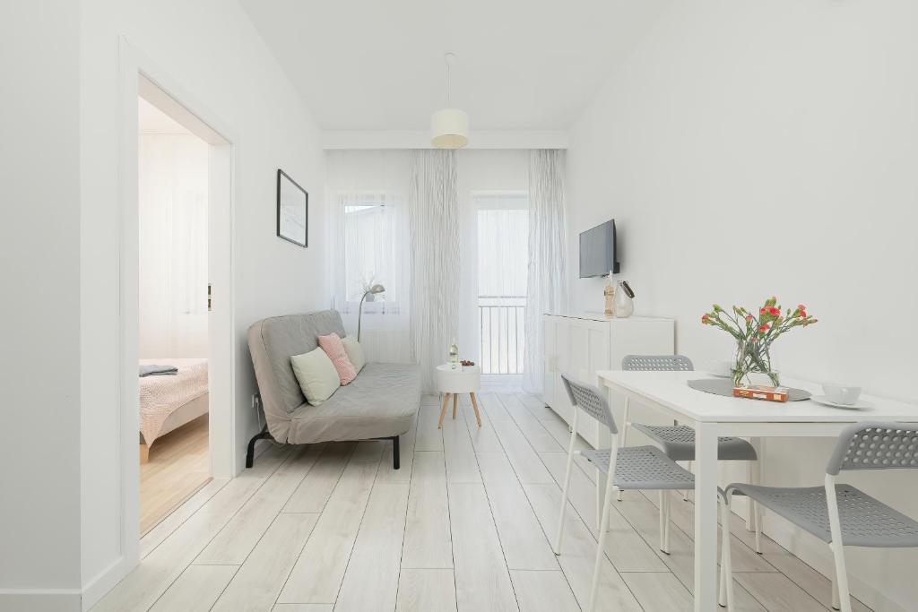 Sala de estar blanca con silla y mesa en Apartament Mewa en Dziwnówek
