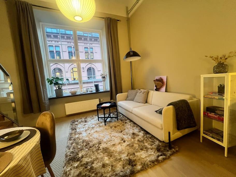 a living room with a white couch and a window at Koselig leilighet i sentrum av OSLO med byutsikt! in Oslo