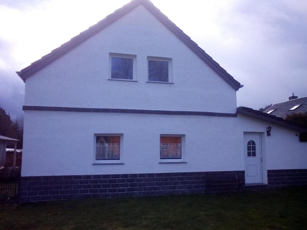 Una casa blanca con tres ventanas en el costado. en Ferienwohnung Eulitz, en Peickwitz