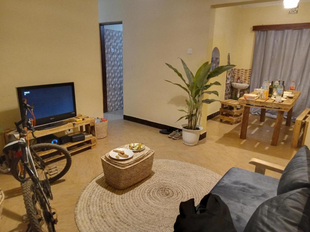 sala de estar con TV de pantalla plana y mesa en Arusha-paradise-home, en Nkoanrua