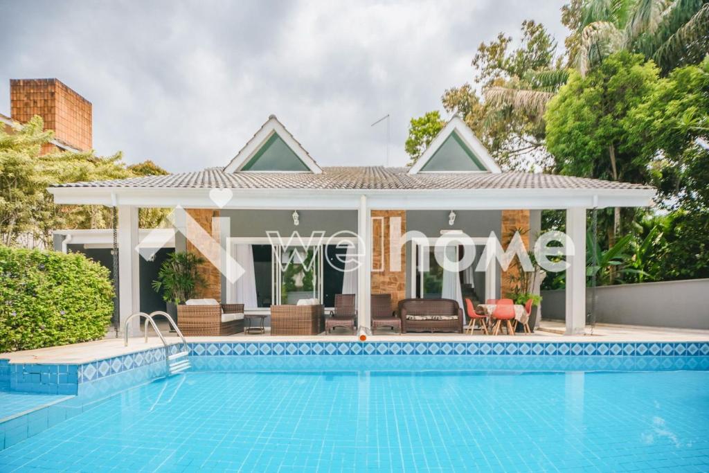 a villa with a swimming pool and a house at Casa com piscina a 10 minutos da praia em Bertioga in Riviera de São Lourenço
