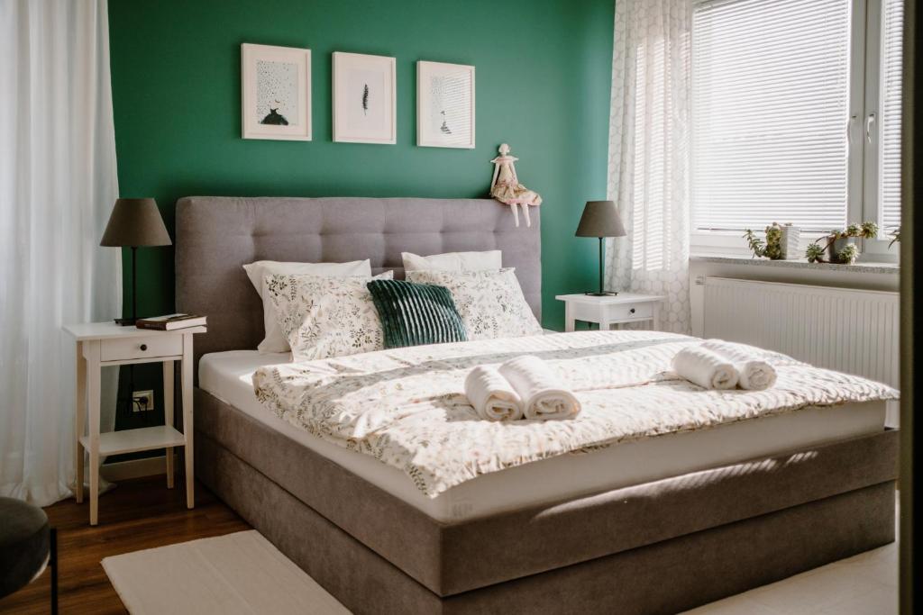 a bedroom with a large bed with green walls at Apartament White in Giżycko