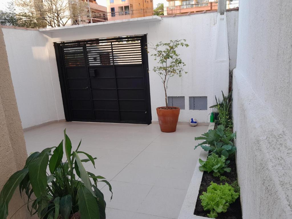 a black door in a white building with plants at Casa pertinho da praia doTombo in Guarujá