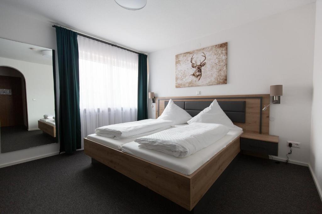 a bedroom with a bed with white sheets and a window at Landgasthof Schützen in Tengen