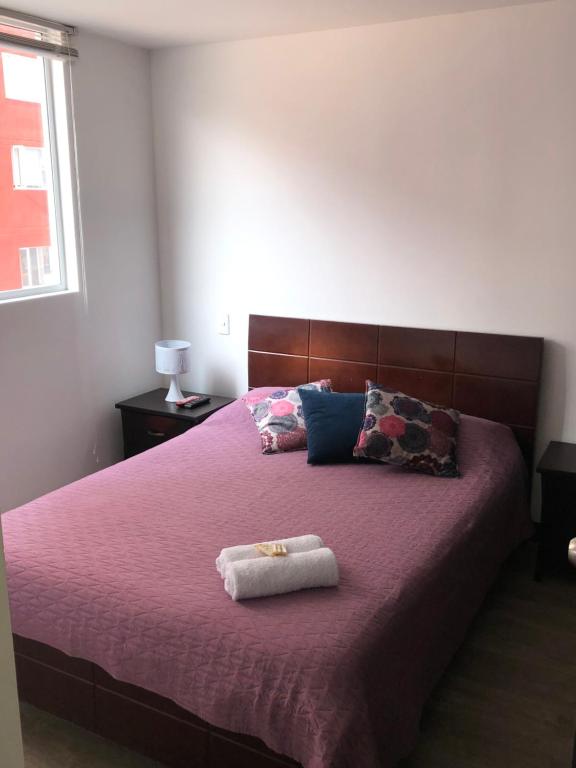 una camera da letto con un grande letto con lenzuola e cuscini viola di Apartamento central a Manizales