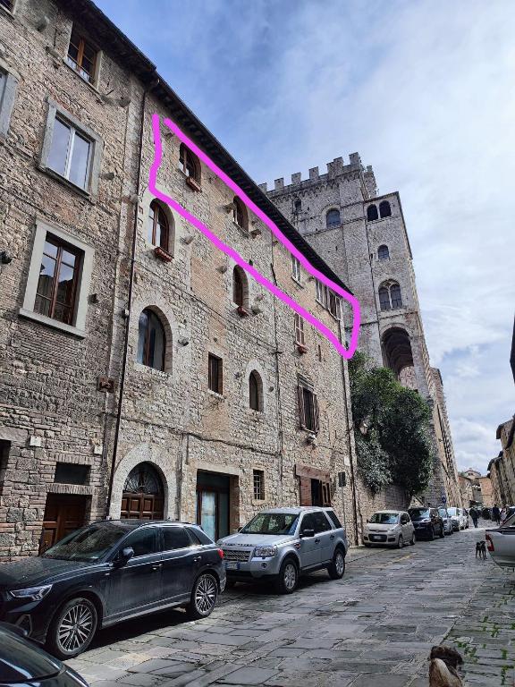 a large brick building with cars parked in front of it at Locazione Gattapone 1A in Gubbio
