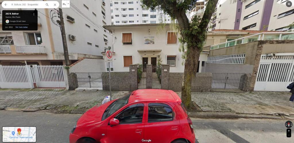 a red car parked in front of a building at Casa de Praia Boqueirão in Santos