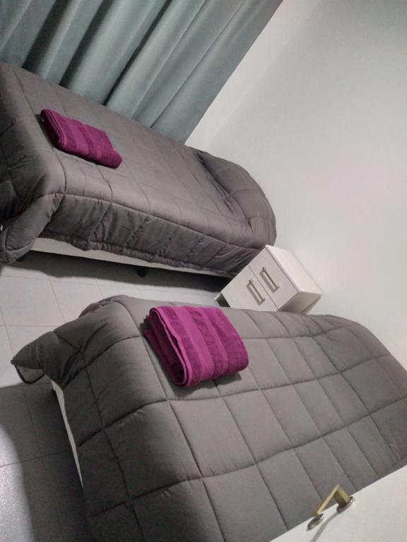 - un lit avec 2 oreillers violets dans l'établissement Alojamiento laura, à Puerto Santa Cruz