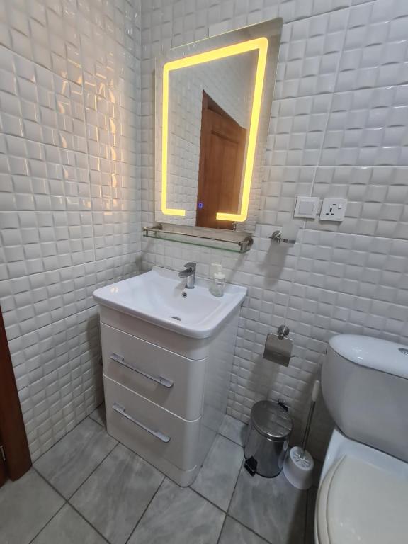 bagno bianco con lavandino e specchio di Bene and Boat Apartments a Madina