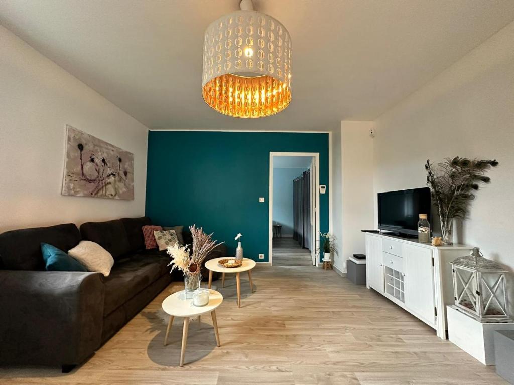 un salon avec un canapé noir et un mur bleu dans l'établissement Charmant 2 pièces avec terrasse - Proche Gare et Centre Ville, à Besançon