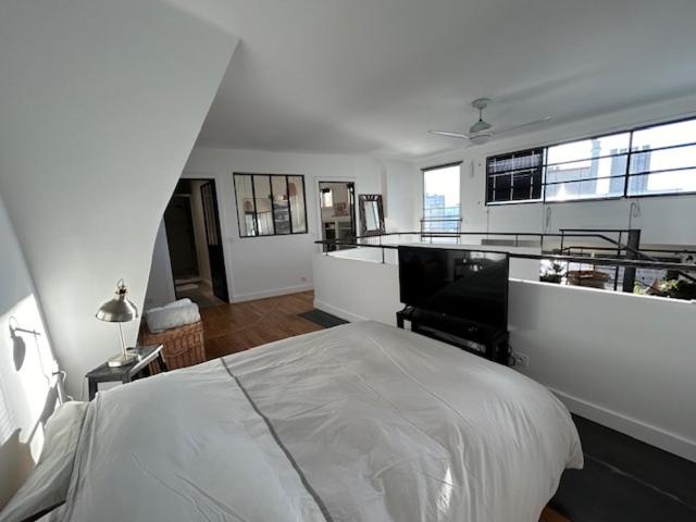 een witte slaapkamer met een bed en een piano bij Duplex apartment with terrace and closed parking - Stade Charléty Paris in Arcueil